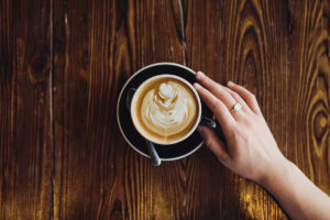 Hände halten eine Tasse mit Latte Art