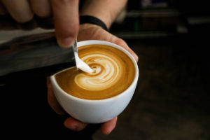 Milch wird für Latte Art in eine Tasse gegossen