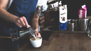 Milch wird in eine Kaffeetasse gegossen