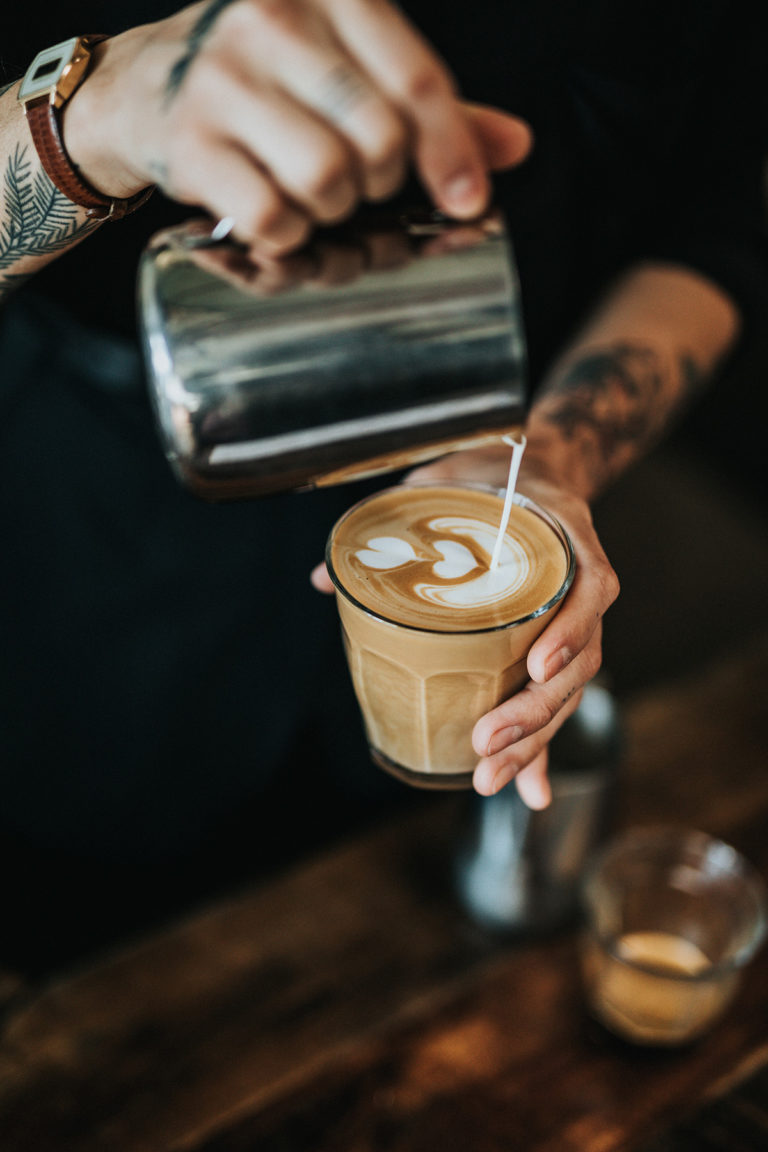 Milchschaum wird für Latte Art in einen Cappuccino gegossen