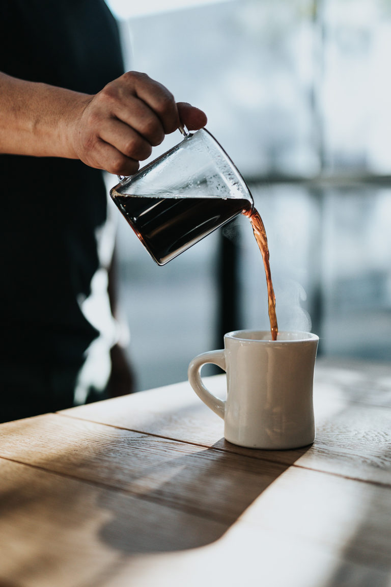 Wasser wird aus einem Kessel in eine Tasse gegossen